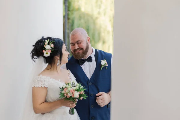 Frischvermählte gehen am Hochzeitstag im Park spazieren, schauen einander an, lächeln. — Stockfoto