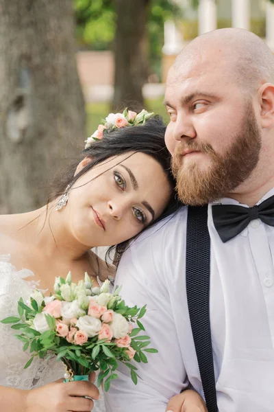 Recién casados se sientan en un banco en el parque . — Foto de Stock