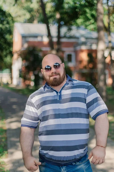 .Jonge man met ronde bril en overgewicht in het park. — Stockfoto