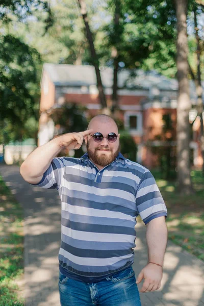 .Jonge man met ronde bril en overgewicht in het park. — Stockfoto