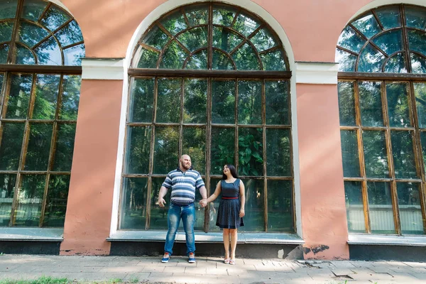 Δύο ερωτευμένα σταθεί αγκάλιασμα από μεγάλα παράθυρα στο πάρκο και να φαίνονται σε κάθε άλλο. — Φωτογραφία Αρχείου