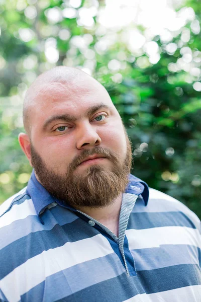 Hombre gordo en el parque mira en el marco, un retrato de un hombre con exceso de peso . — Foto de Stock