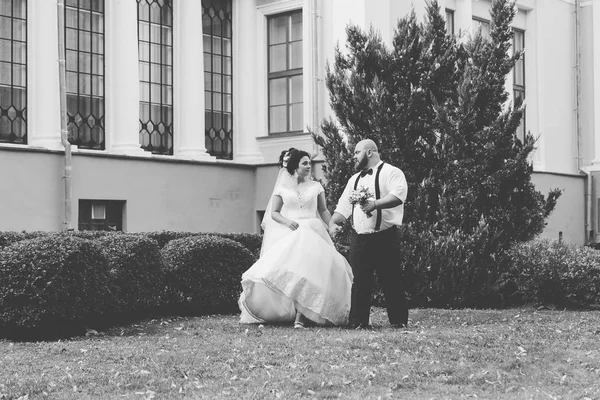 Jonggehuwden op hun trouwdag lopen in het park, kijkend naar elkaar, glimlachend. — Stockfoto