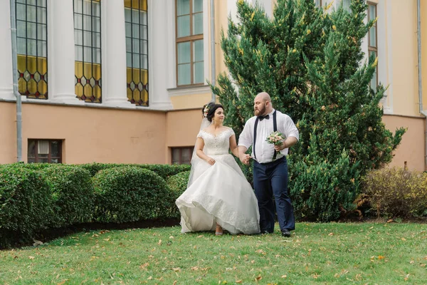 Recém-casados no dia do casamento estão andando no parque, olhando um para o outro, sorrindo . — Fotografia de Stock