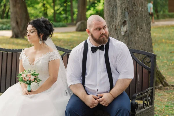 Recién casados se sientan en un banco en el parque . — Foto de Stock