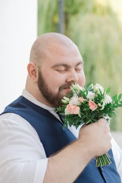 Elegante noivo gordo barbudo com buquê de casamento no parque . — Fotografia de Stock