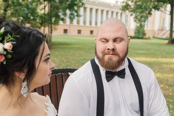 Recién casados se sientan en un banco en el parque . — Foto de Stock