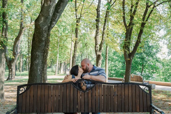 Two people in love are standing at the bench in the park. — Stock Photo, Image