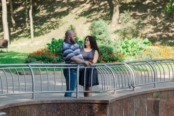 Twee mensen in liefde staan op de niet-actieve fontein in het park. — Stockfoto