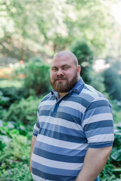 Dikke man in het park ziet er in het frame, een portret van een man met overgewicht. — Stockfoto