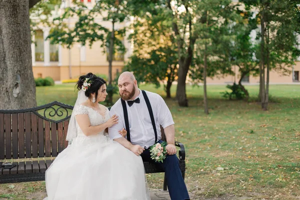 新婚夫妇坐在公园的长凳上. — 图库照片