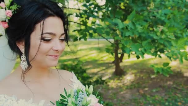 Όμορφη νύφη με γαμήλια ανθοδέσμη στο πάρκο. — Αρχείο Βίντεο