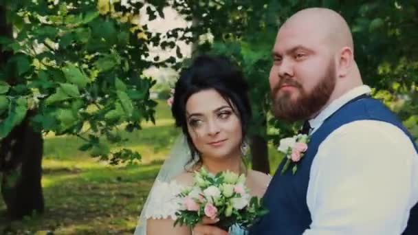 Felices recién casados caminando, abrazándose, besándose en el parque . — Vídeo de stock