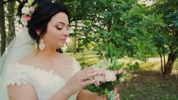 Krásná nevěsta s svatební kytice v parku. — Stock video