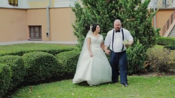 Felices recién casados caminando, abrazándose, besándose en el parque . — Vídeos de Stock