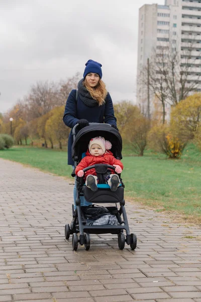 Женщина гуляет в парке с коляской и маленьким ребенком . — стоковое фото