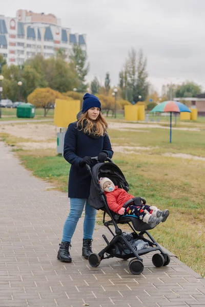 Женщина гуляет в парке с коляской и маленьким ребенком у озера . — стоковое фото