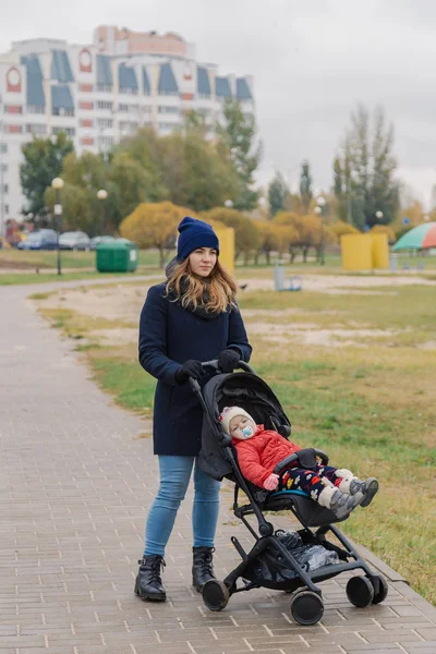 Женщина гуляет в парке с коляской и маленьким ребенком у озера . — стоковое фото