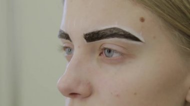 Güzel genç kız bir güzellik salonu içinde absorbe olmak için kaş boya bekliyor.