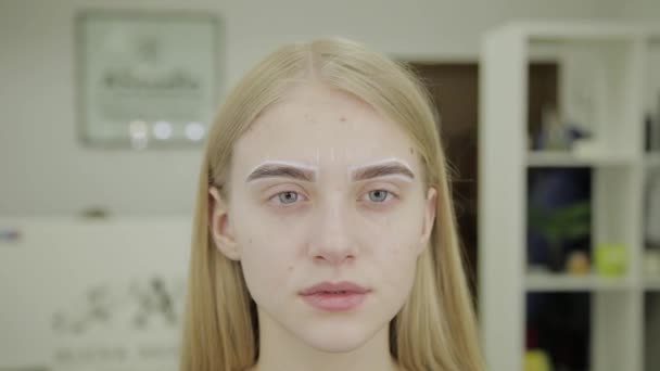 Portret van een mooi meisje met ingelijste wenkbrauwen voor kleuren in een schoonheidssalon. — Stockvideo