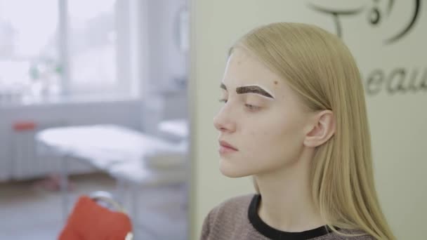 Maquiagem artista faz coloração de sobrancelha com corantes naturais, tonificação com henna, procedimentos cosméticos no salão de beleza . — Vídeo de Stock