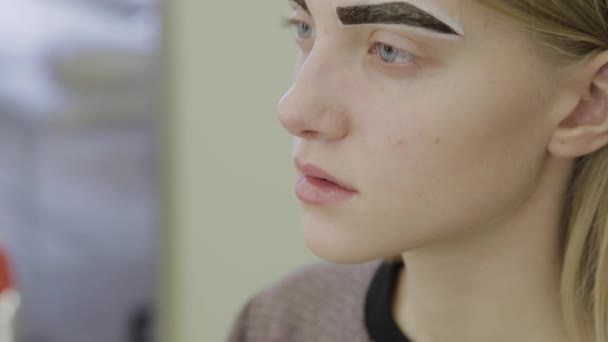 美丽的年轻女孩在美容院等待眉毛油漆被吸收. — 图库视频影像