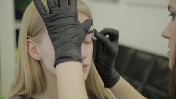 Limpe as sobrancelhas com um disco de algodão para uma jovem após o procedimento de coloração . — Vídeo de Stock