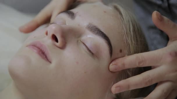 Relaxing woman having a massage for her skin on a face in salon. — Stock Video