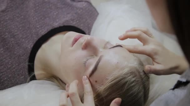 リラックスした女性サロンで顔に彼女の肌のためのマッサージを持っています。. — ストック動画