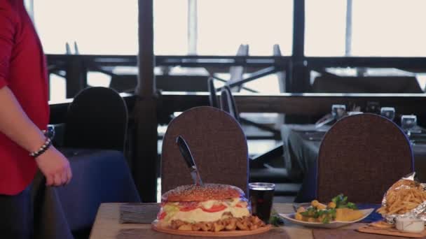 El hombre de la mesa lleva guantes para comer una hamburguesa. . — Vídeo de stock