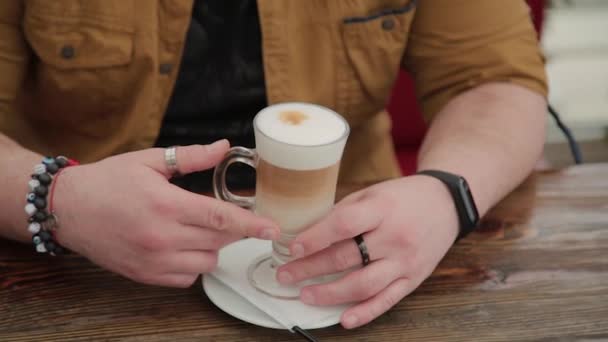 Hombre bebiendo café con leche en la terraza de la mesa . — Vídeos de Stock