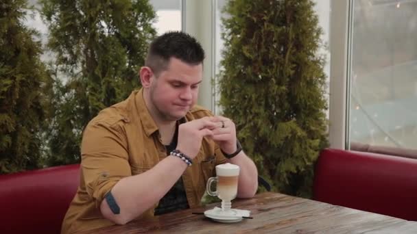 Man latte drinken op de veranda aan de tafel. — Stockvideo