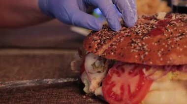 Bir adam büyük bir burger bir bıçakla keser..