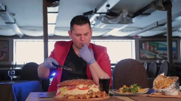 Um homem corta um hambúrguer enorme com uma faca . — Vídeo de Stock