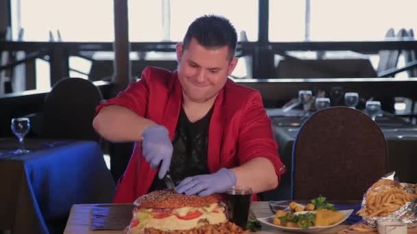 En man skär en enorm hamburgare med en kniv. — Stockvideo