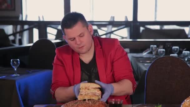 Мужчина берет бургер и пробует свой язык. . — стоковое видео