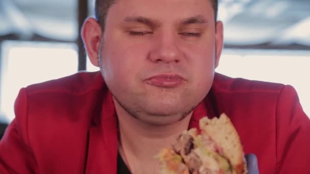 El gordo es feo comiendo una hamburguesa grande. . — Vídeo de stock