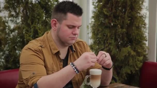 Hombre bebiendo café con leche en la terraza de la mesa . — Vídeos de Stock