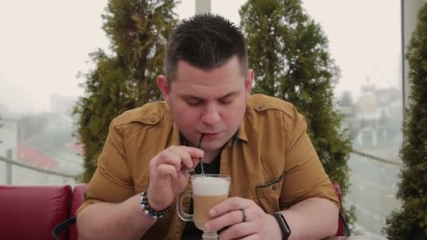 Mann trinkt Latte auf der Veranda am Tisch. — Stockvideo