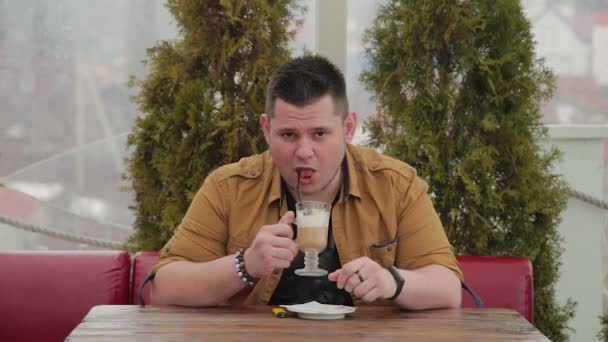 Człowiek pije latte na werandzie przy stole. — Wideo stockowe