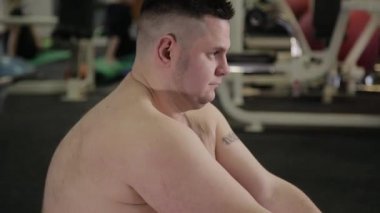 Spor salonunda yerde uzanan yapan şişman erkek.