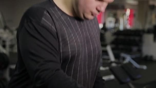 Gros homme exerçant sur le tapis roulant dans la salle de gym . — Video