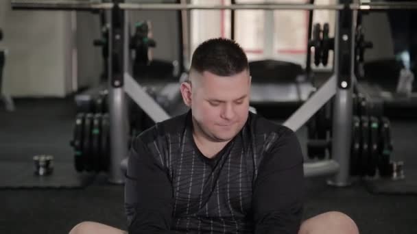 Fat man doing stretching on the floor in the gym. — Stock Video