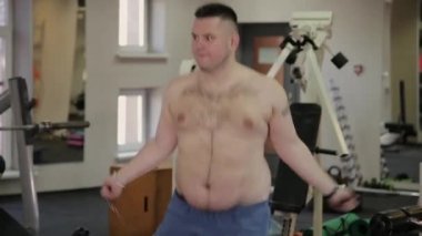 Şişman adam spor salonunda ip atlama.