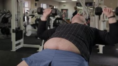 Şişman adam spor salonunda dumbbells ile eğitim.