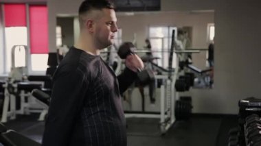 Şişman adam spor salonunda dumbbells ile eğitim.