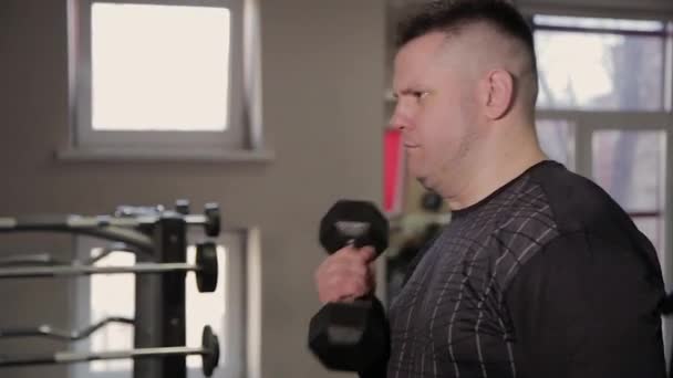 Şişman adam spor salonunda dumbbells ile eğitim. — Stok video