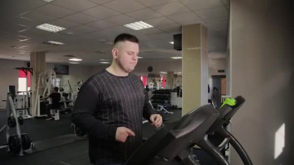 Gros homme exerçant sur le tapis roulant dans la salle de gym . — Video