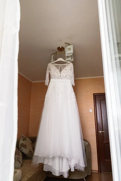 Vestido de novia muy hermoso de la novia colgando en la lámpara de araña en la habitación . —  Fotos de Stock