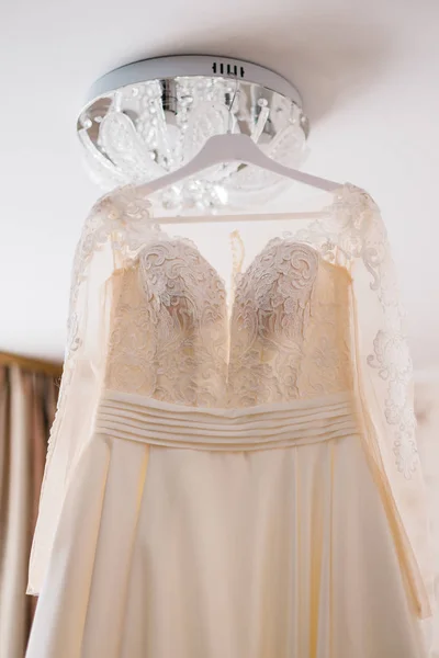 Vestido de novia muy hermoso de la novia colgando en la lámpara de araña en la habitación . —  Fotos de Stock